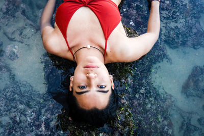 High angle portrait of young woman lying at beach