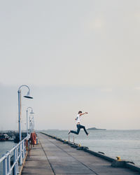 People on pier by sea against sky