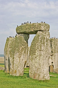 Stone structure on grassy field against sky