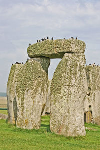 Stone structure on grassy field against sky