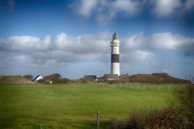 Lighthouse on field against sky