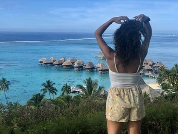 Rear view of woman standing at beach against sky tiny house lagoon fare pote polynesian style