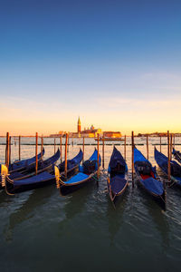 Boats moored in canal against sky during sunset