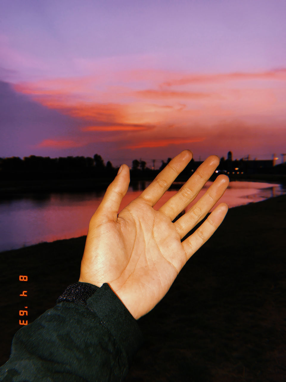 CROPPED IMAGE OF HAND AGAINST ORANGE SKY