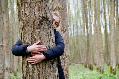 Woman embracing tree at forest