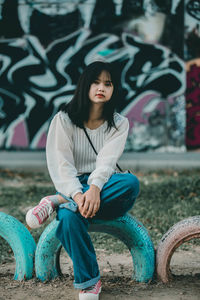 Full length of young woman sitting outdoors