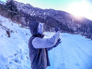Rear view of woman standing on snow covered mountain
