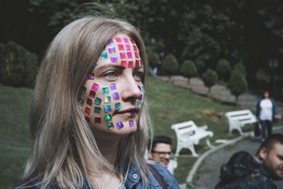 Close-up of mid adult woman with colorful stickers on face
