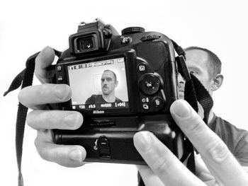 Close-up of hand holding camera against white background