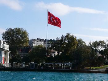 Red flag by trees against sky