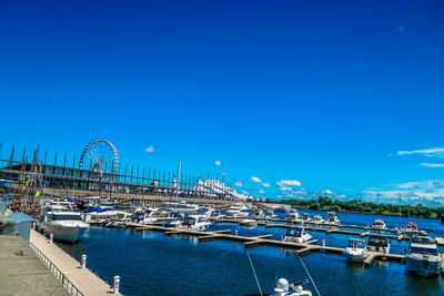 Sailboats moored in harbor against blue sky