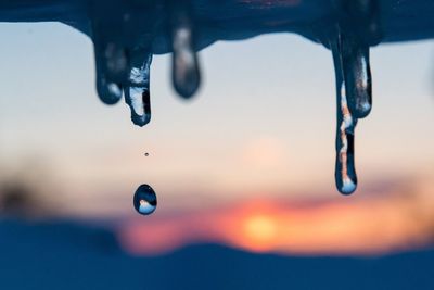 Close-up of water drop in mid-air during sunset