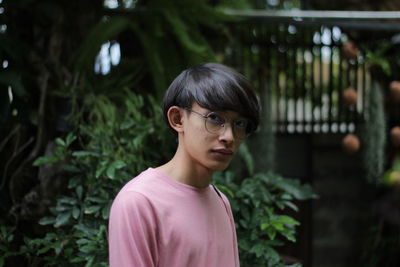 Portrait of teenage boy standing against plants