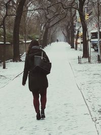 Rear view of man walking on snow covered landscape