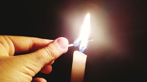 Close-up of hand holding burning candle