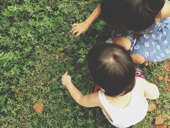 High angle view of siblings touching plants on field