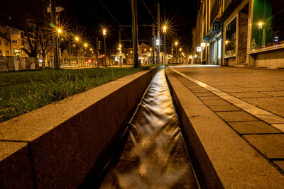 Surface level of empty road along buildings at night