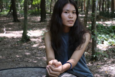 Portrait of beautiful young woman sitting in forest