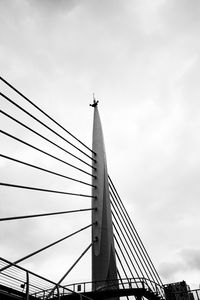 Low angle view of suspension bridge against cloudy sky