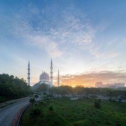 Mosque in city against sky during sunset