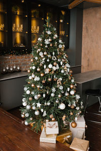 Decorated gold and silver christmas tree with gifts under it for the new year in the loft-style 