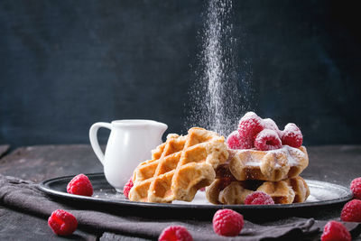 Close-up of waffles with raspberries in plate on table