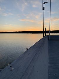 Silhouette of a pire by lake against sky during sunset