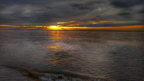 Scenic view of sea against cloudy sky at sunset