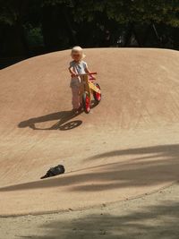 Girl with bicycle walking on hill in park