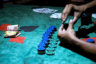 Cropped image of hand playing poker chips on table