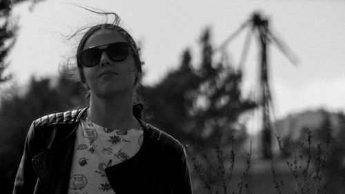 Portrait of young woman wearing sunglasses standing against sky