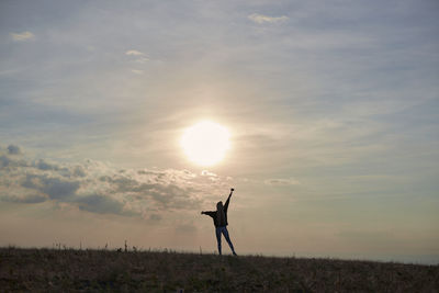 Man standing on field against sky during sunset