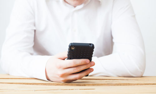 Midsection of man using smart phone on table