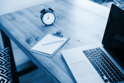 High angle view of clock and laptop on table