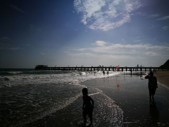 Silhouette people on beach against sky