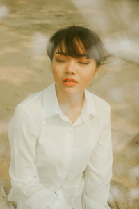 Young woman with eyes closed sitting outdoors