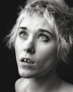 Close-up portrait of young woman against black background