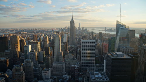 Aerial view of buildings in city against cloudy sky