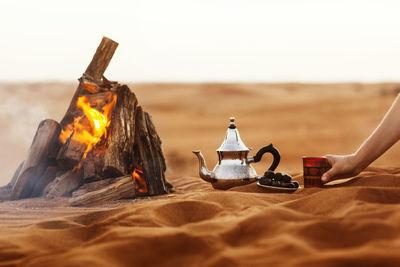Dates, teapot, cup with tea near the fire in the desert with a beautiful background, ramadan kareem