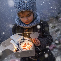 Girl in knitted grey hat opening a gift box with warm gloves