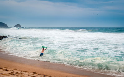 Rear view of man in sea against cloudy sky