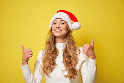 Portrait of smiling young woman against yellow background