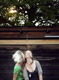 Happy sisters enjoying against wooden wall