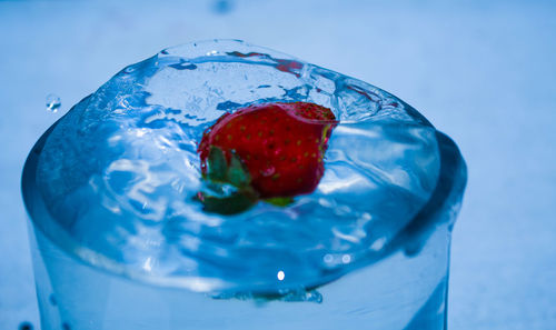 Close-up of strawberry falling in glass with water