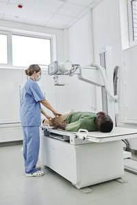 Nurse wearing scrubs taking x-ray shot of patient in clinic