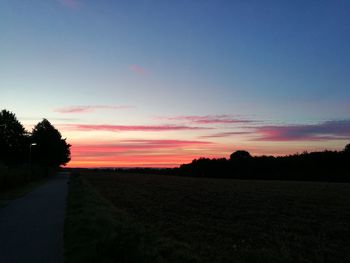 Silhouette of trees on landscape at sunset