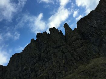 Low angle view of rocks against cloudy sky