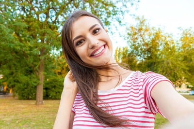 Portrait of smiling beautiful woman standing at park