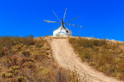 Windmill on field against clear blue sky