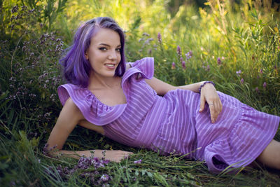 Teenage girl with dyed purple hair and a nose piercing in the grass  in a short dress